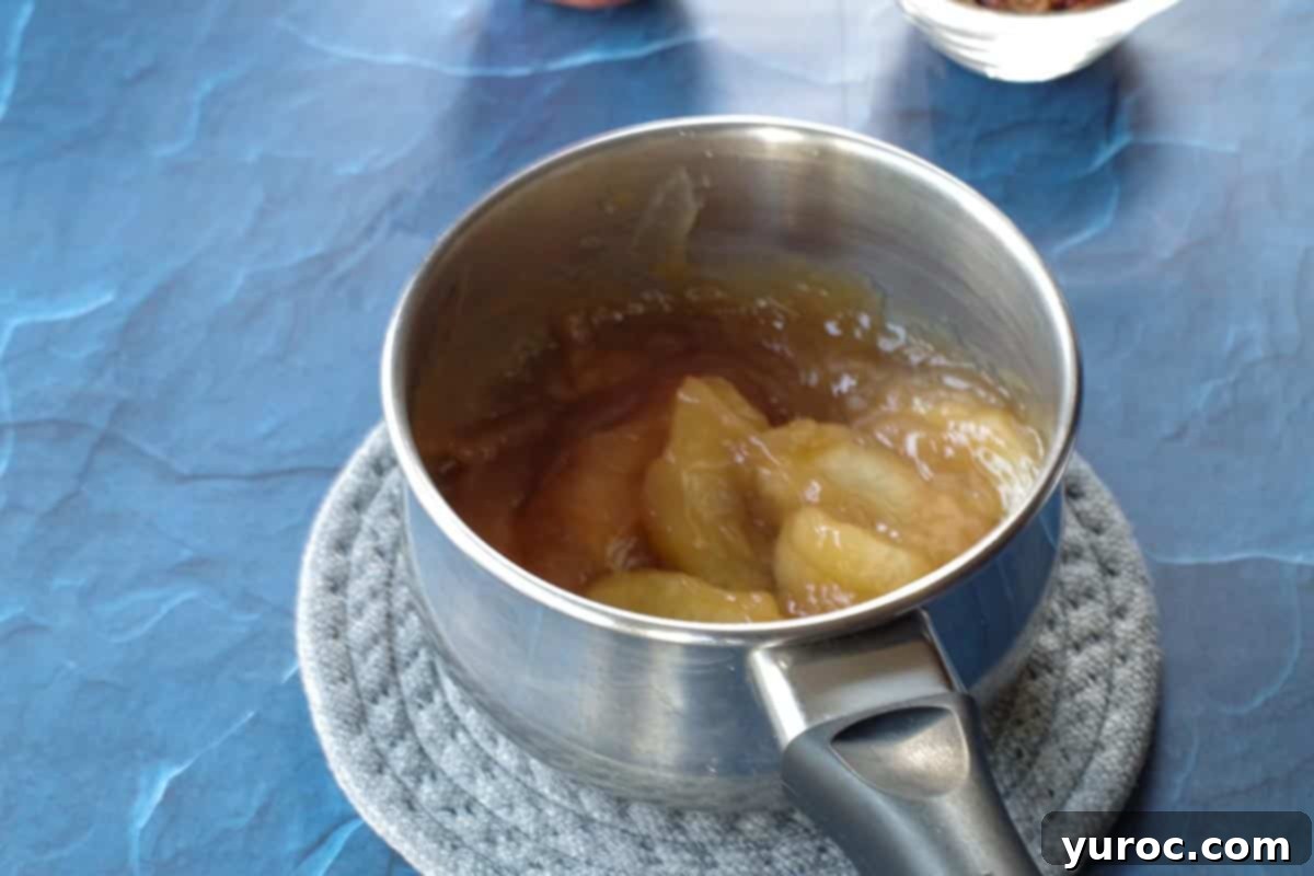 The reserved apple pie filling and caramel sundae sauce combined in a small saucepan, heating gently on the stovetop to create the pie topping.