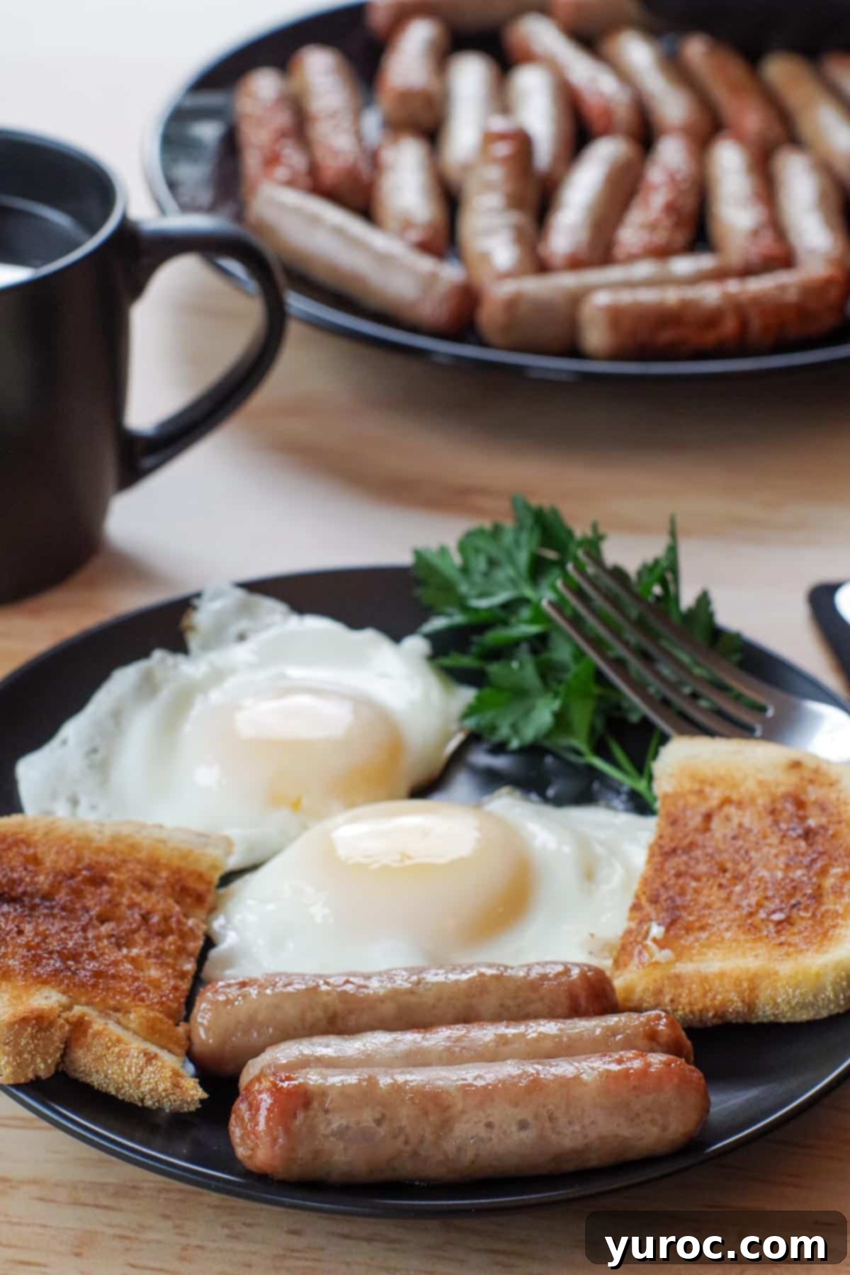 3 air fryer turkey sausages on a black plate with eggs and toast and a plate of more sausage in the background