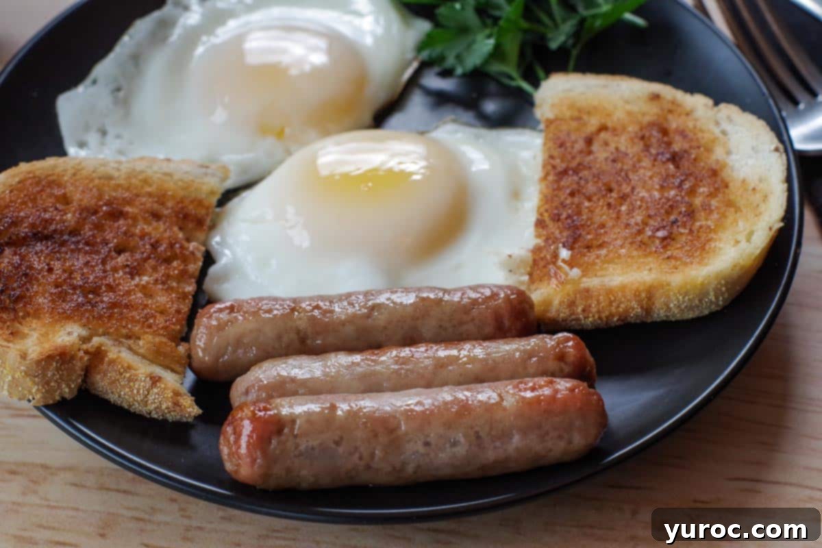 3 air fryer turkey sausages on a black plate with eggs and toast and parsley