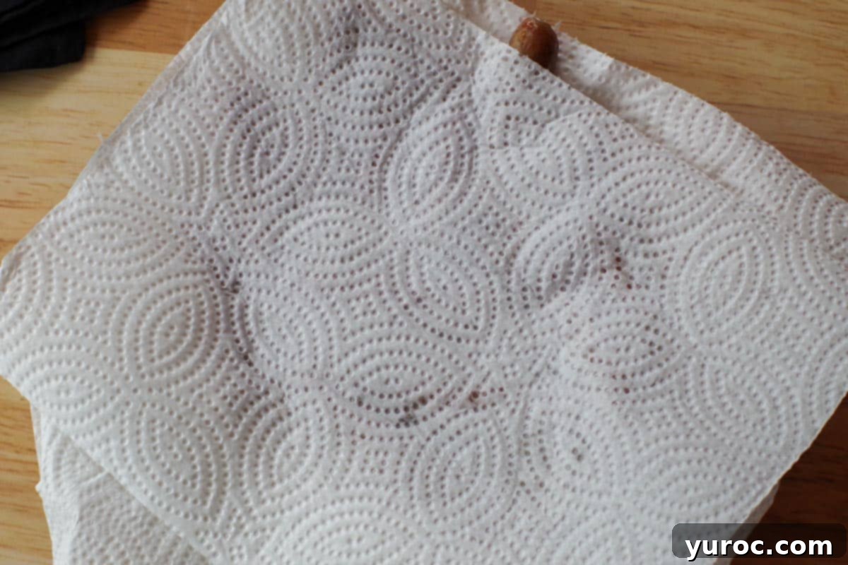 turkey sausage being patted dry with paper towel from top.