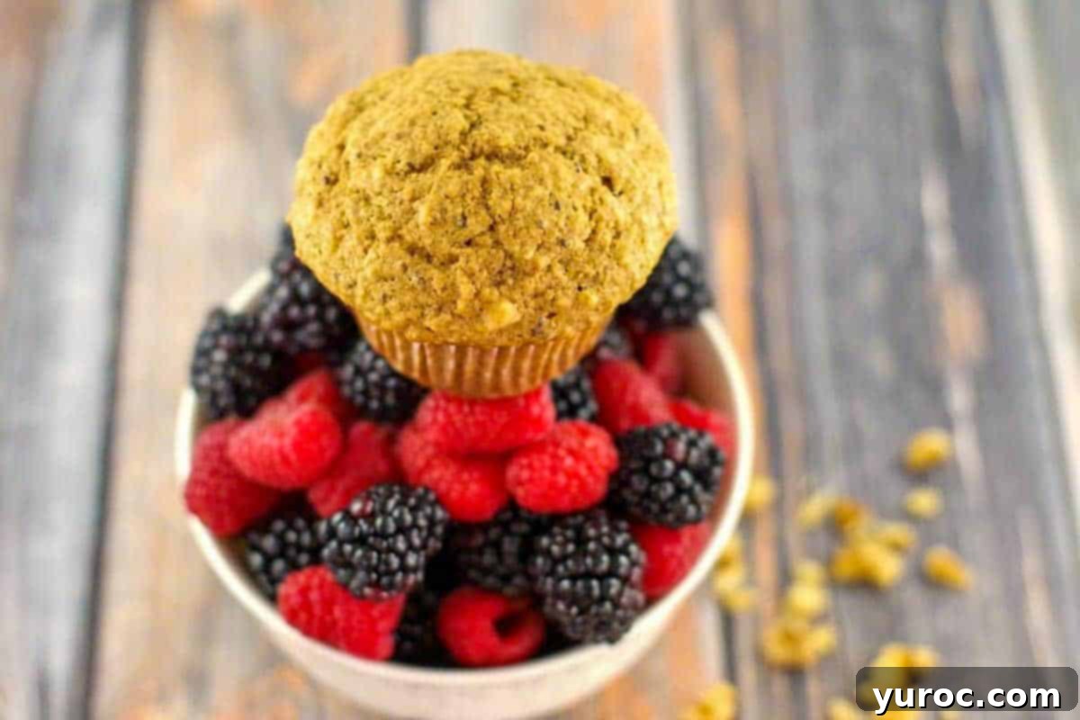 A Wheat Bran Muffin sitting on top of a bowl of fresh mixed berries, with walnuts scattered beside the bowl.