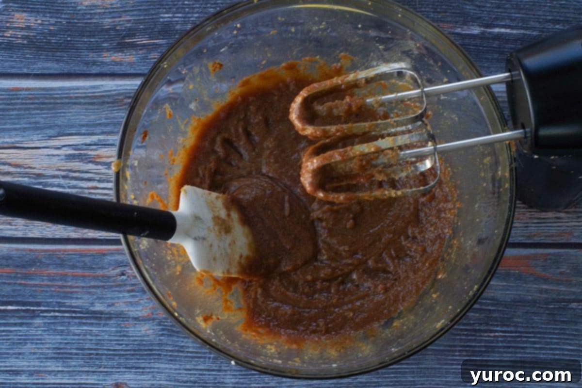 Oil and molasses beaten into butter and brown sugar mixture in a large glass bowl with a spatula and beaters.