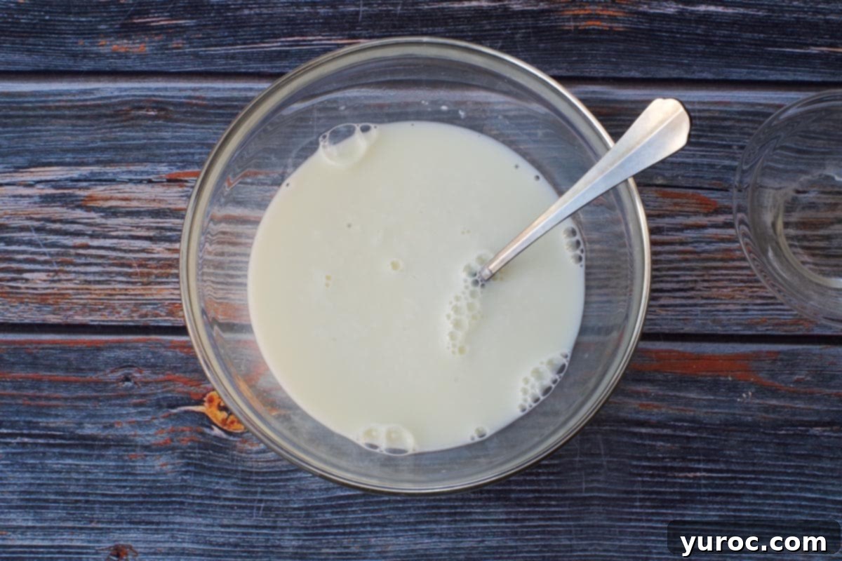 Baking soda added to milk and stirred together in medium glass bowl with a spoon.