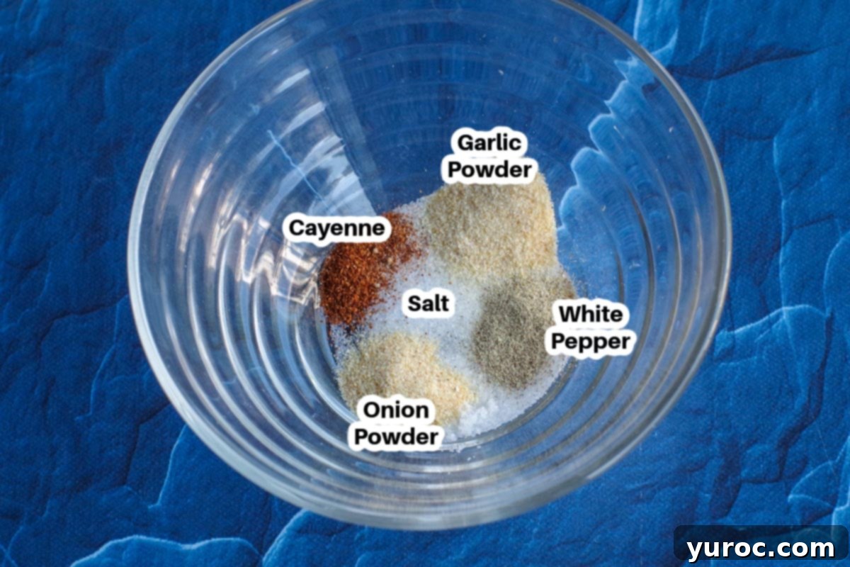 A small glass bowl filled with the precise blend of spices for the sweet potato fries dip, with each spice labeled individually.