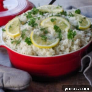 Greek rice with lemon and herb garnish in orange dish