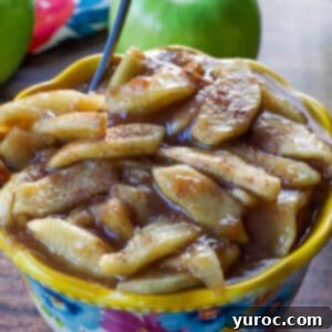 stovetop apple pie filling in a flowered blue bowl with yellow rim, with spoon and cinnamon stick in it