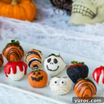 Halloween chocolate covered strawberries on a white long rectangular platter with skull and pumpkin decorations in background