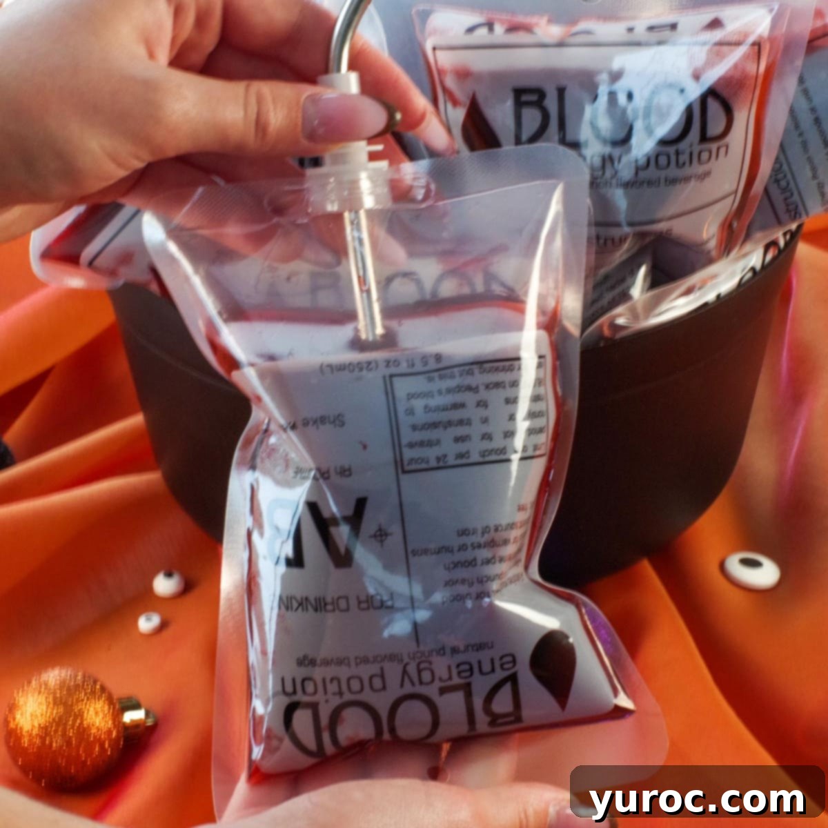 Halloween blood bag with a straw in it and more blood bags in a cauldron in the background