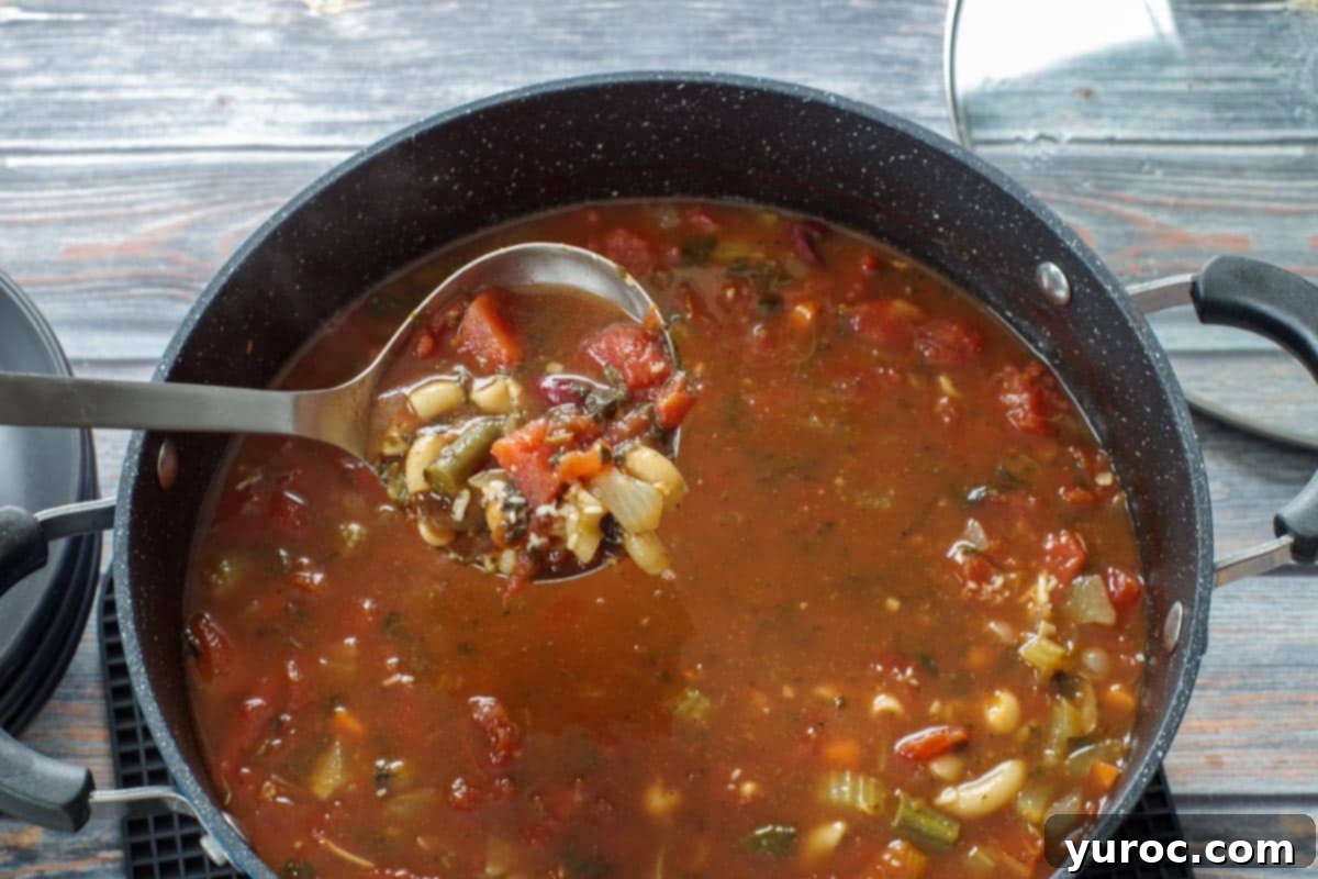 Wholesome Minestrone Made Easy 10 A ladle full of rich, colorful minestrone soup being lifted from a large pot, showcasing the hearty vegetables and pasta within.