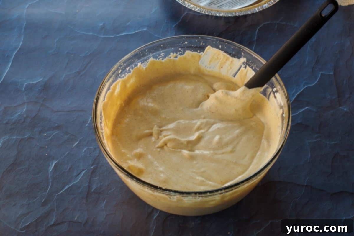The pumpkin ice cream mixture, now fully combined and smooth, in a large glass bowl, ready to be transferred.