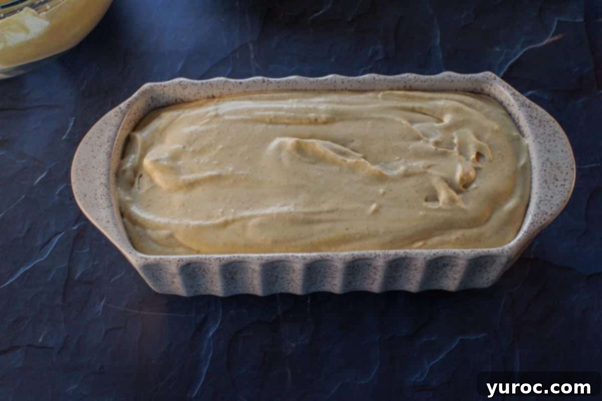 The prepared pumpkin pie ice cream mixture poured into a ceramic loaf pan, ready for freezing.