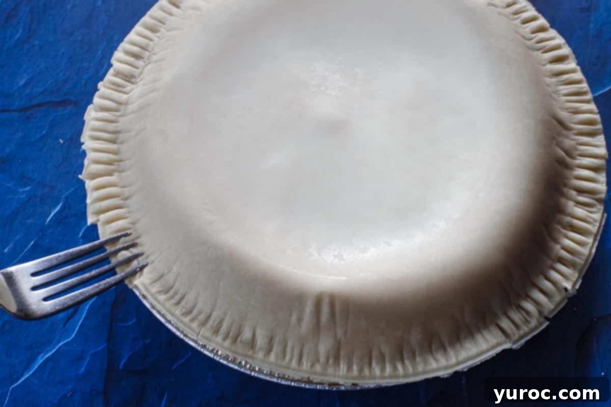 Edge of pie being crimped with a fork