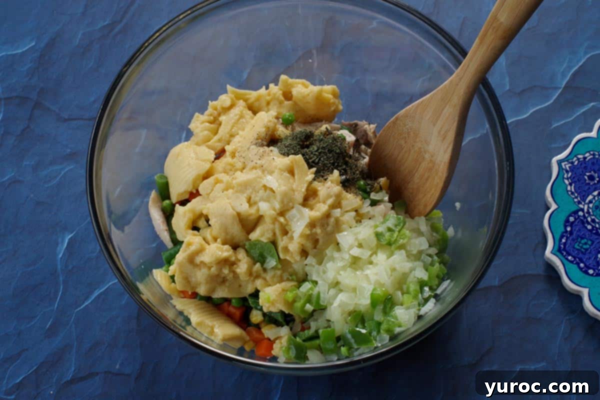 All turkey pot pie ingredients in a large glass bowl with a wooden spoon