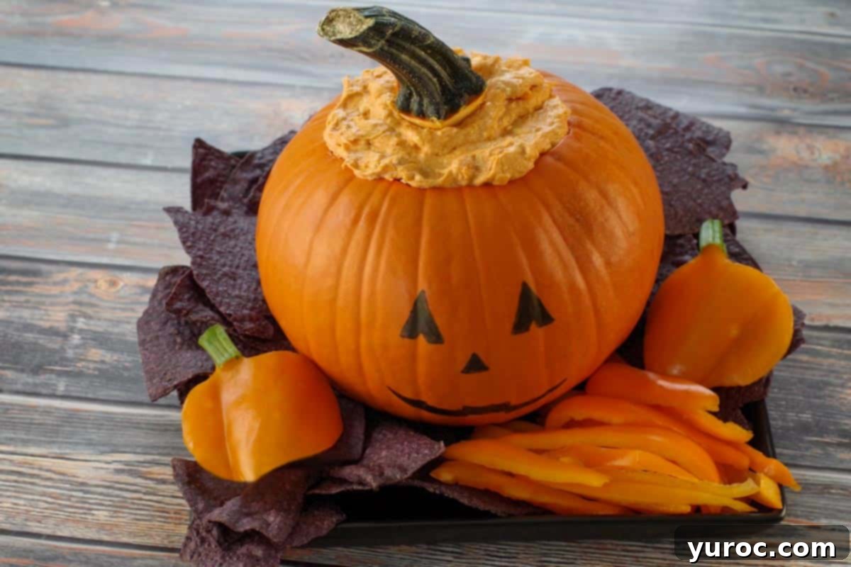 Halloween Buffalo Chicken Dip on a black platter with black nacho chips and orange peppers