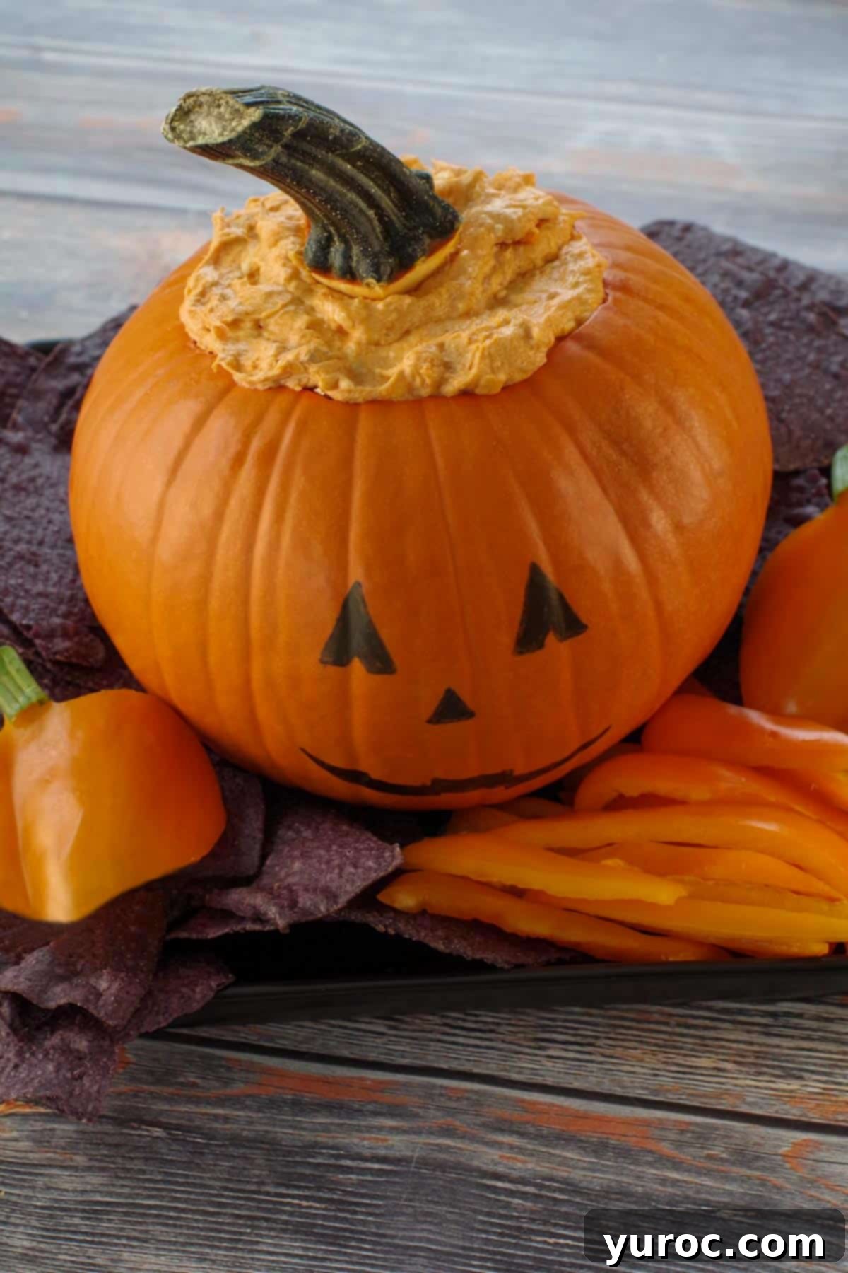 Halloween Buffalo Chicken Dip on a black platter with black nacho chips and orange peppers