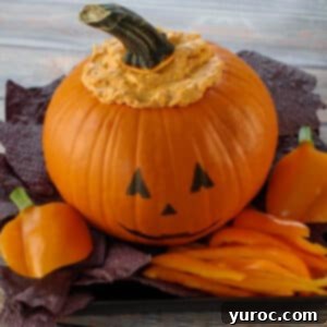 Halloween Buffalo Chicken Dip on a black platter with black nacho chips and orange peppers