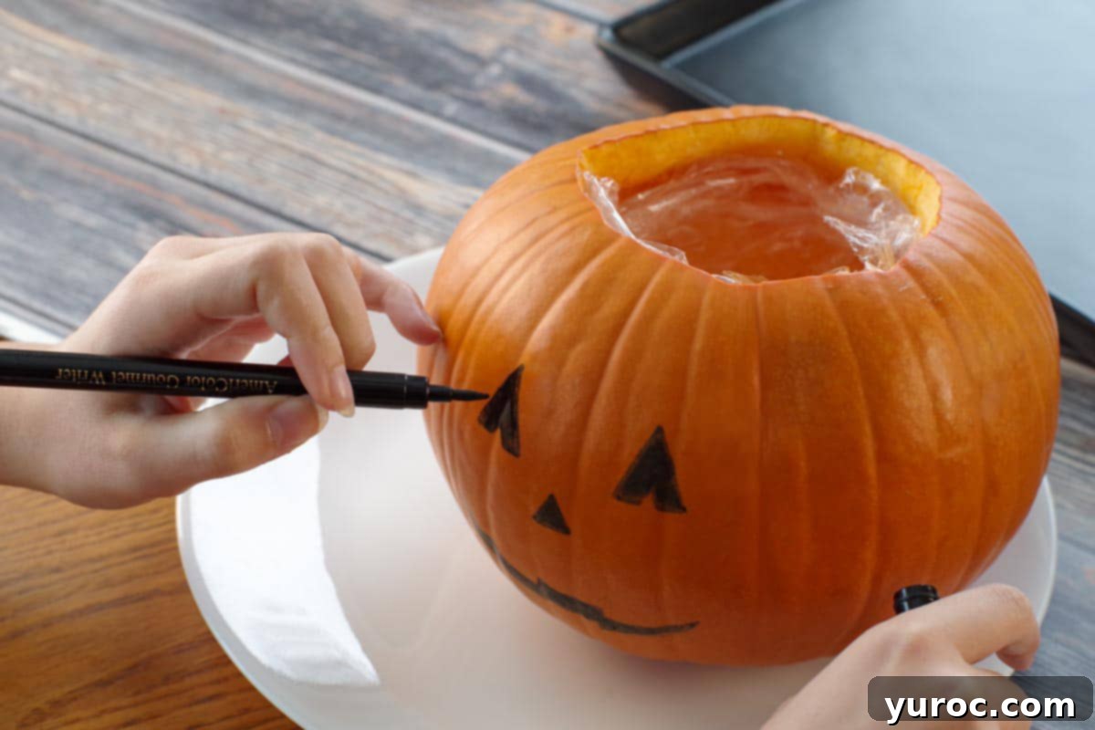 face being drawn on pumpkin with edible marker