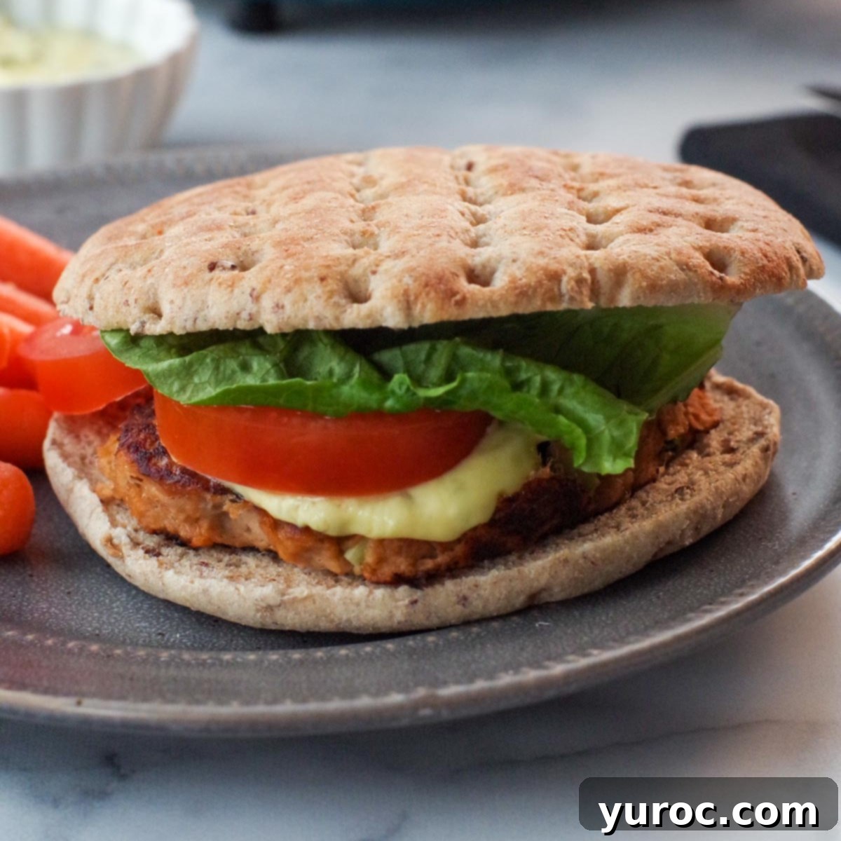 A delicious tuna burger presented on a grey plate, ready to be enjoyed with parsnip fries.