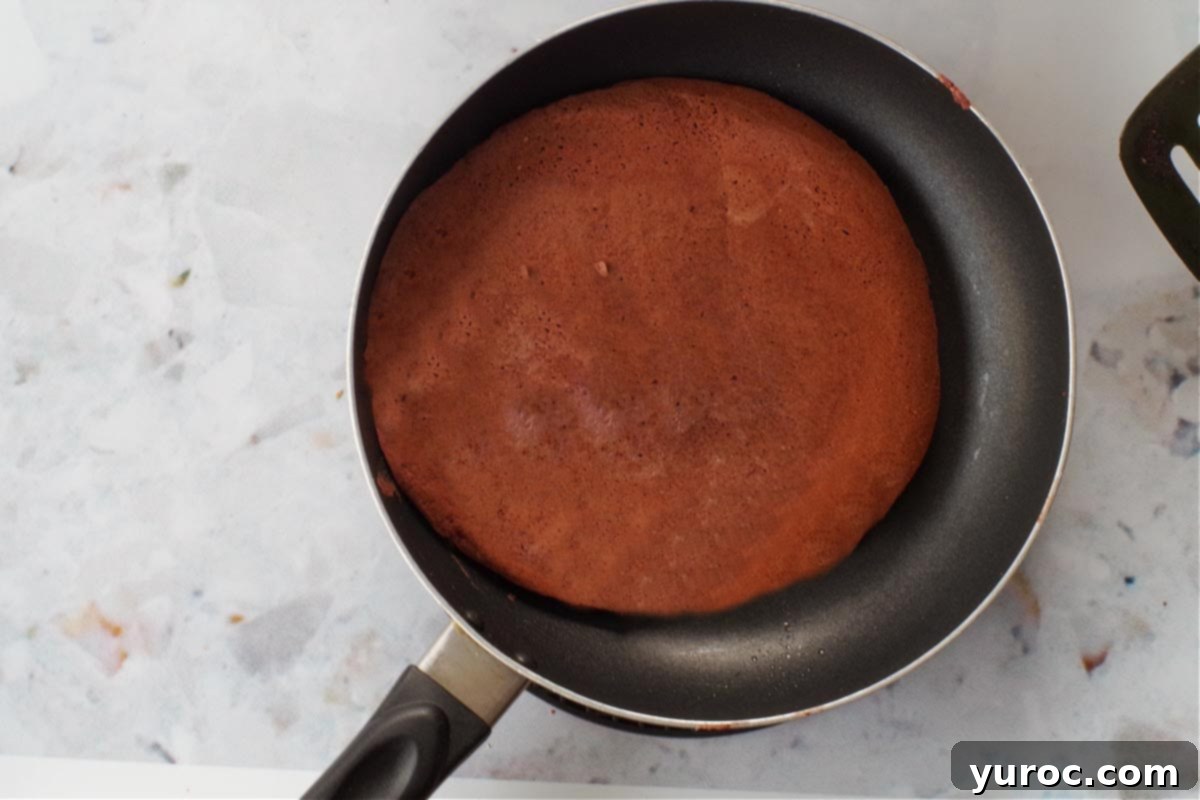 Healthy Red Velvet Pancakes with Luscious Chocolate Cream Cheese Butter 13 A healthy red velvet pancake, perfectly flipped and cooked, resting in an 8-inch frying pan.