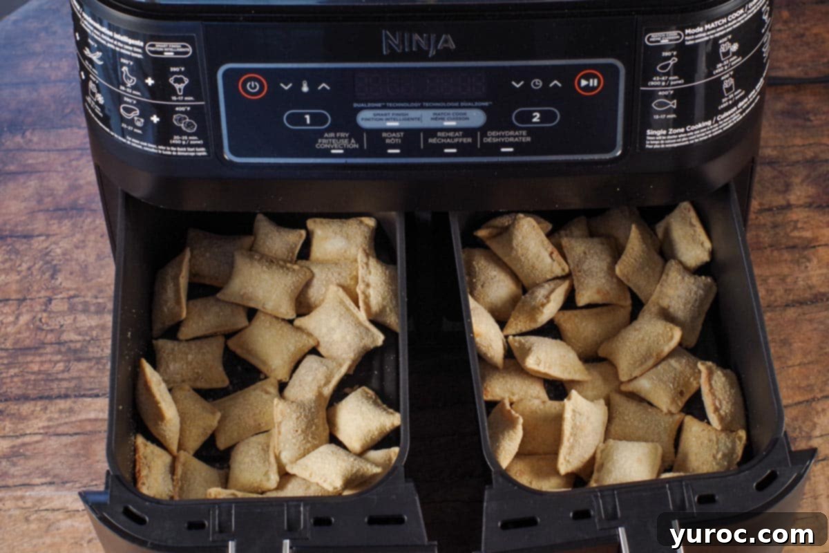 Frozen pizza bites arranged in a single layer in the drawer of an air fryer, ready for cooking.