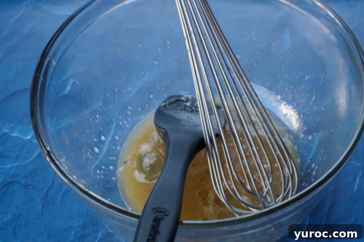 leftover pecan pie filling in large glass bowl with metal whisk and black silicone spatula