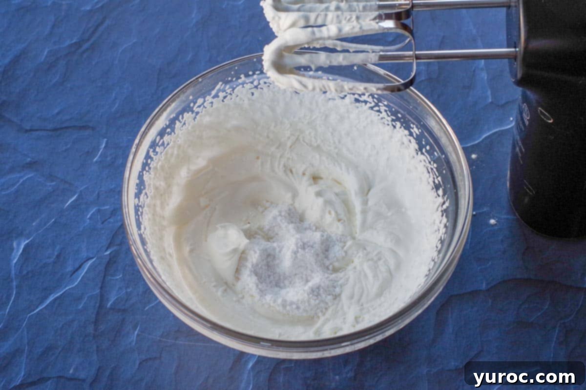 Whipped cream in glass bowl, beaten to soft peaks with powdered sugar and bourbon