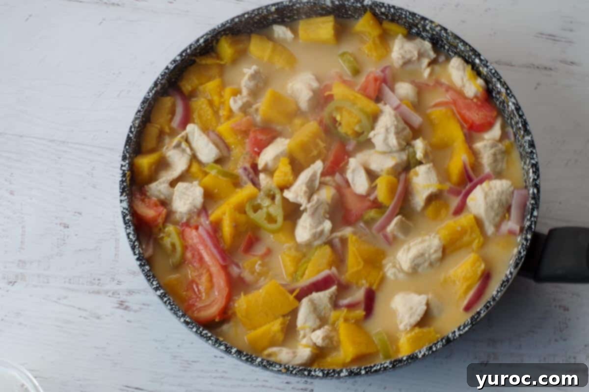 The finished Coconut Pumpkin Chicken dish simmering in a frying pan, indicating it's fully cooked and ready for the final touches.