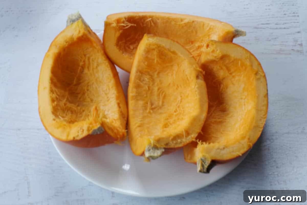 Microwaved pumpkin quarters resting on a white plate, indicating they have been softened for easier handling.