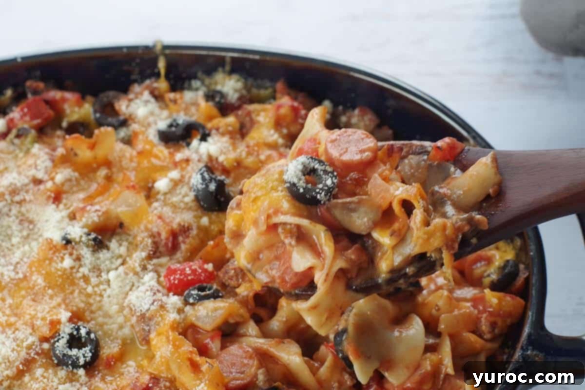 Guilt Free Pizza Casserole 10 spoonful of pizza casserole being held up on a dark wooden spoon over casserole dish