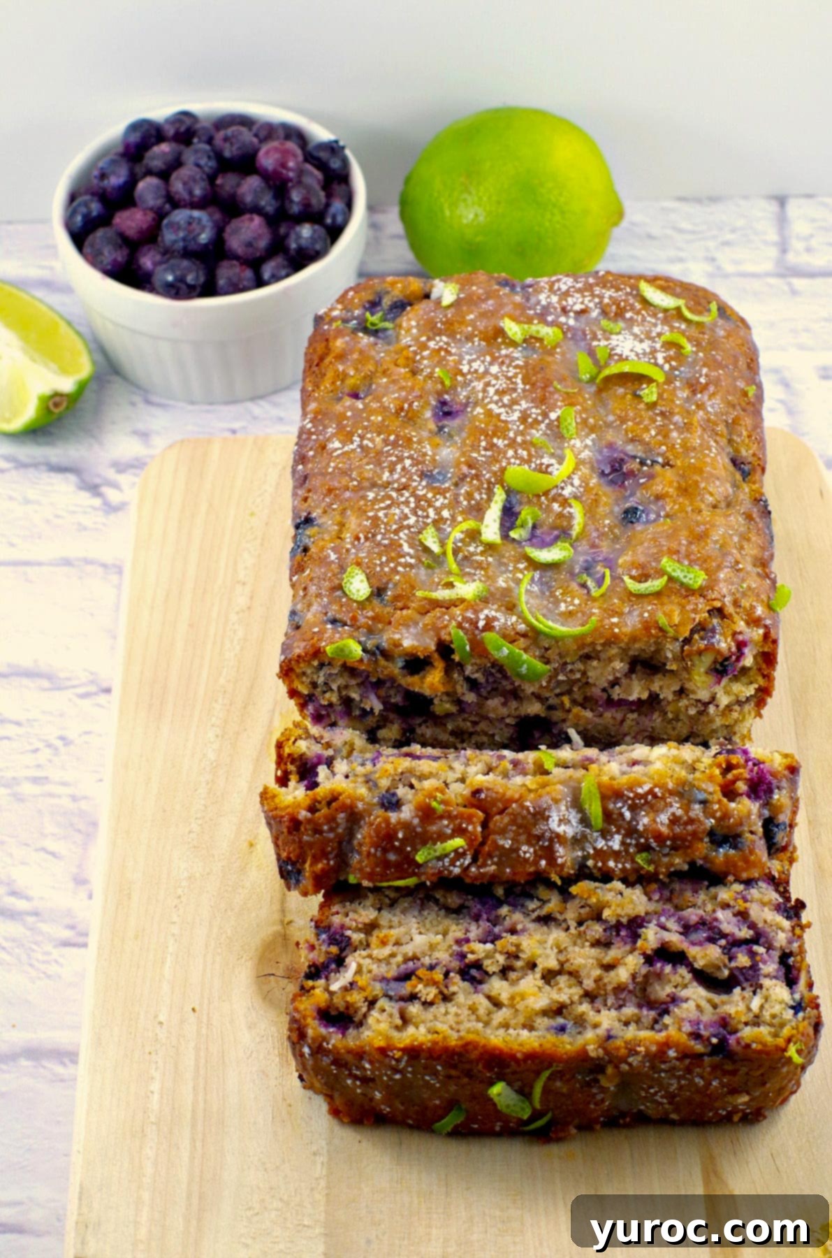 Cozy Blueberry Gingerbread Loaf 14 gingerbread loaf on a cutting board with blueberries and limes in background