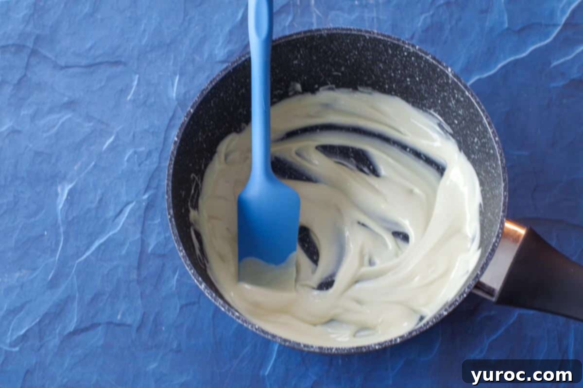 melted white chocolate in a pot with blue spatula