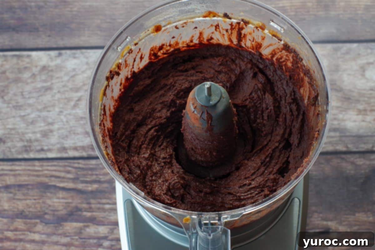 Decadent Dark Chocolate Date Hummus 7 Smooth and creamy dark chocolate hummus is shown after being fully processed in the bowl of a food processor, ready for the final touch.
