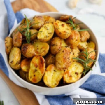 Rosemary Garlic Potatoes in a white bowl, with a blue and white striped linen underneath