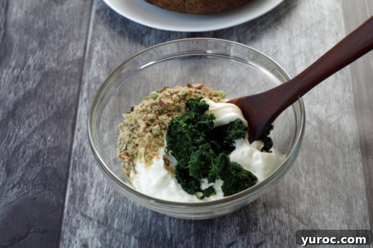 Ultimate Pumpernickel Spinach Dip 3 Spinach dip ingredients in a glass bowl, ready to be mixed with a wooden spoon.