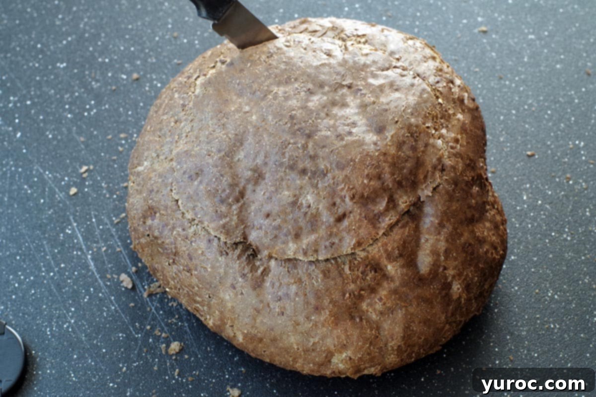 Ultimate Pumpernickel Spinach Dip 6 A knife cutting into the top of a round pumpernickel loaf to create a bread bowl.