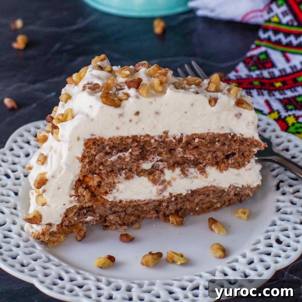 Slice Ukrainian Walnut Torte on a white plate with a whole cake in background