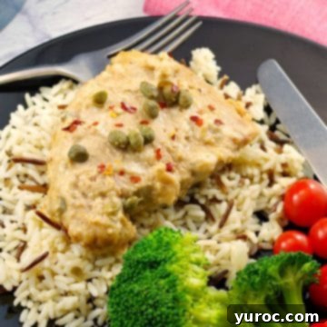 pork with creamy mustard caper sauce on a bed of rice, with salad and tomatoes on the side