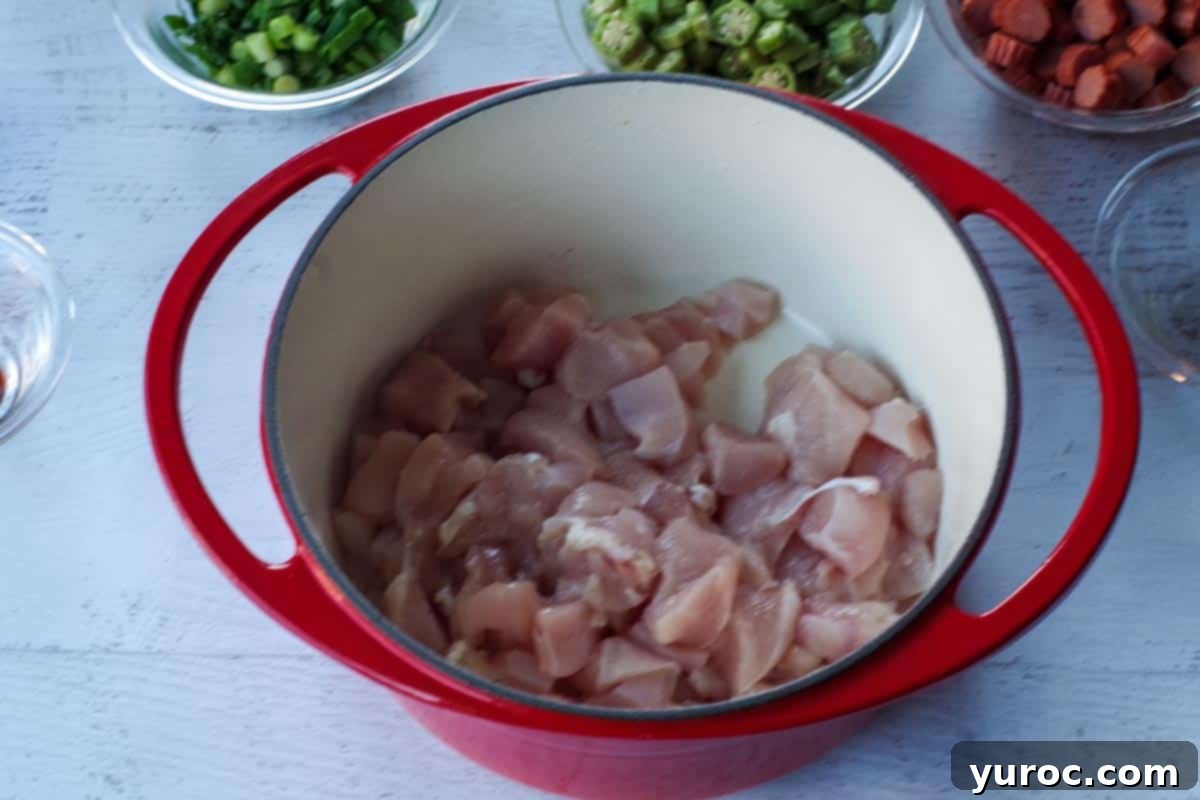 cubed, raw chicken in an orange Dutch oven