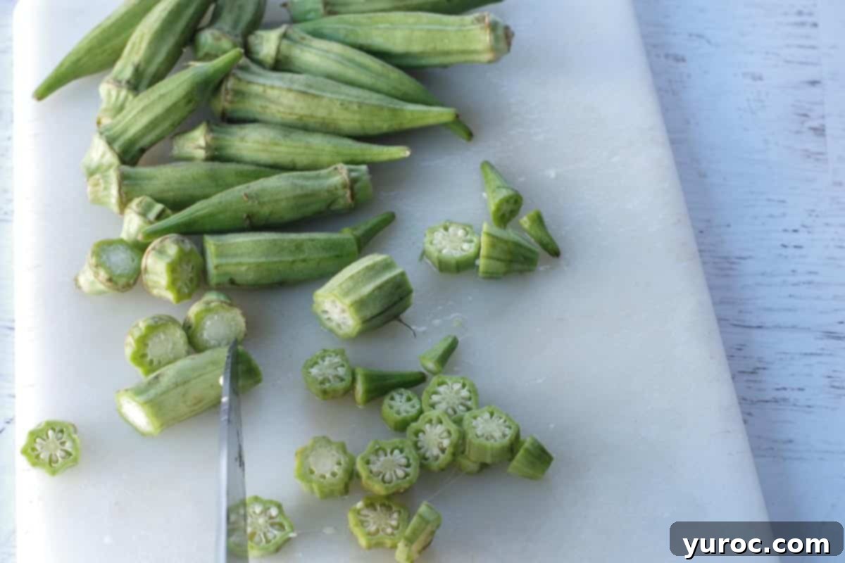 okra being sliced on a white cutting board