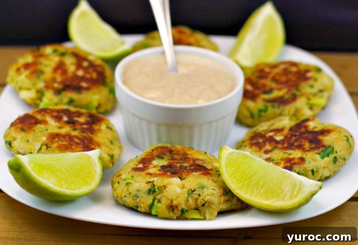 Golden Salmon Cakes with Zesty Ginger Lime Cream 2 Pan-fried salmon patties on white plate, with dip in the middle and lime wedges
