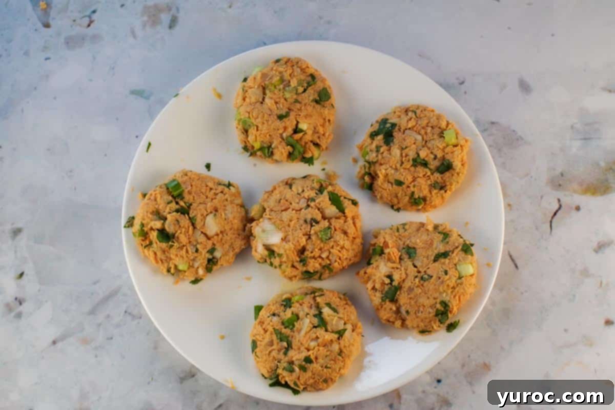 Golden Salmon Cakes with Zesty Ginger Lime Cream 7 6 uncooked salmon patties on a white plate.