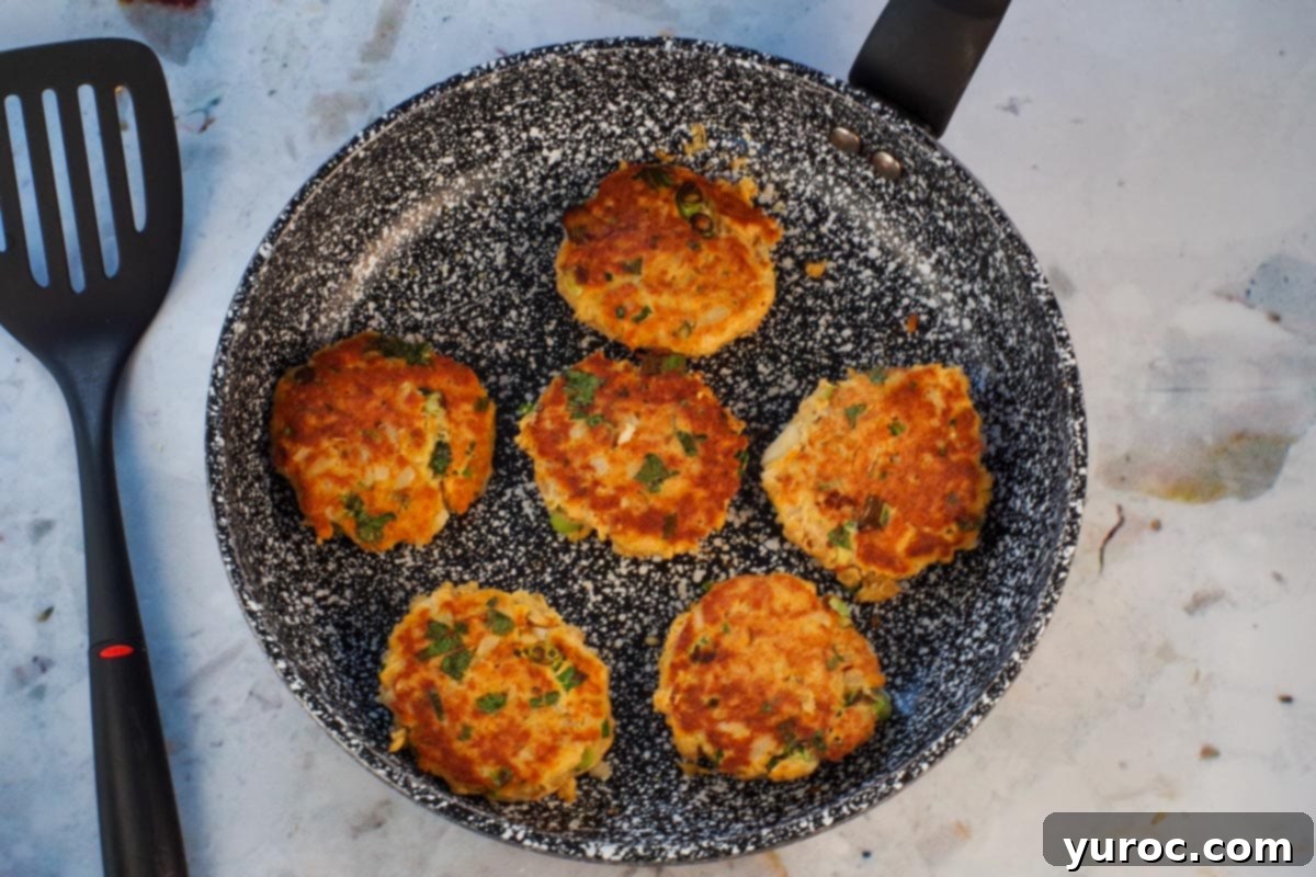 Golden Salmon Cakes with Zesty Ginger Lime Cream 8 6 salmon patties in frying pan cooked on one side.