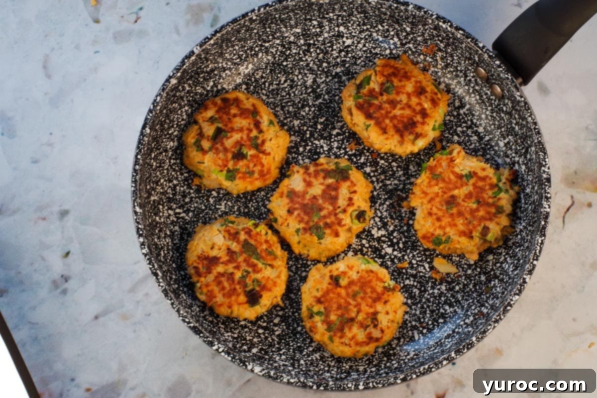 Golden Salmon Cakes with Zesty Ginger Lime Cream 9 Salmon patties cooked on both sides in frying pan.