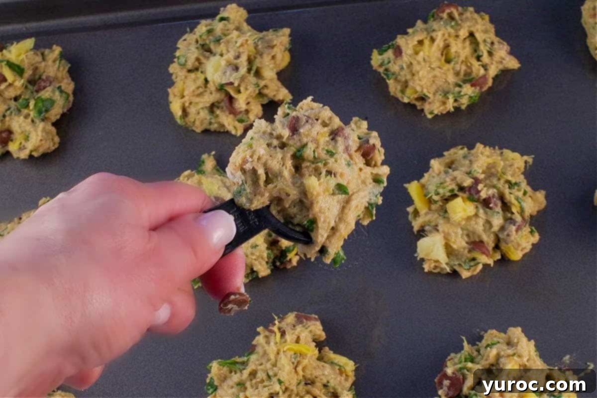 Cookie dough being dropped by the heaping tablespoonful onto cookie sheet.