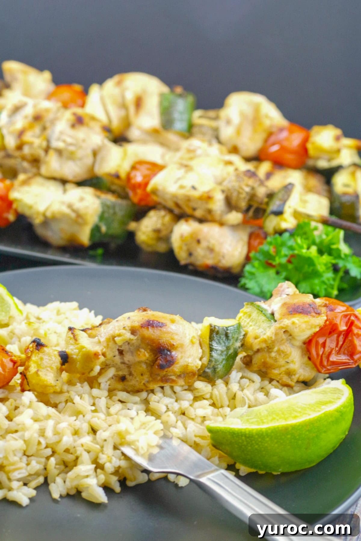 Kabob on rice pilaf with lime and tray of kabobs in background