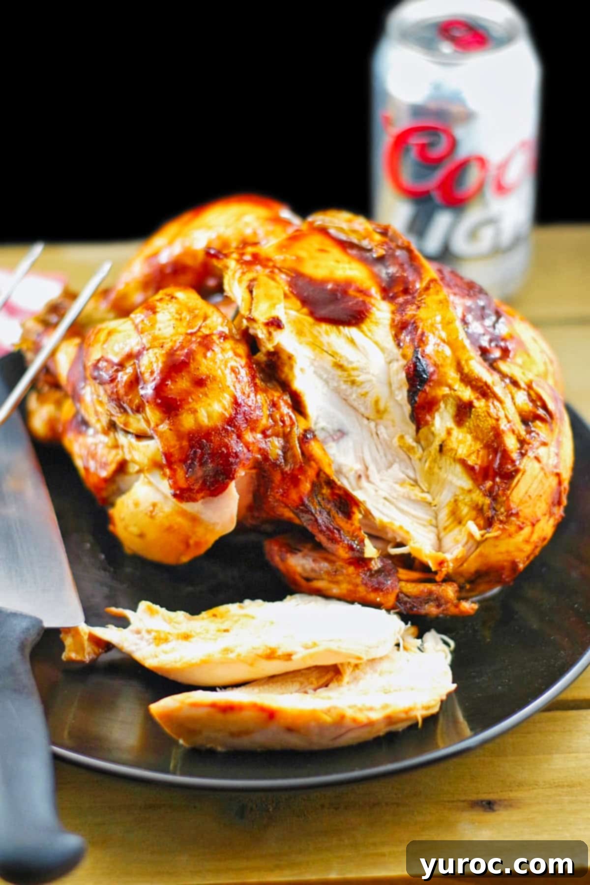 BBQ Beer Can Chicken 2 beer can chicken, sliced, on a black plate, with a knife, and a can of beer in the background