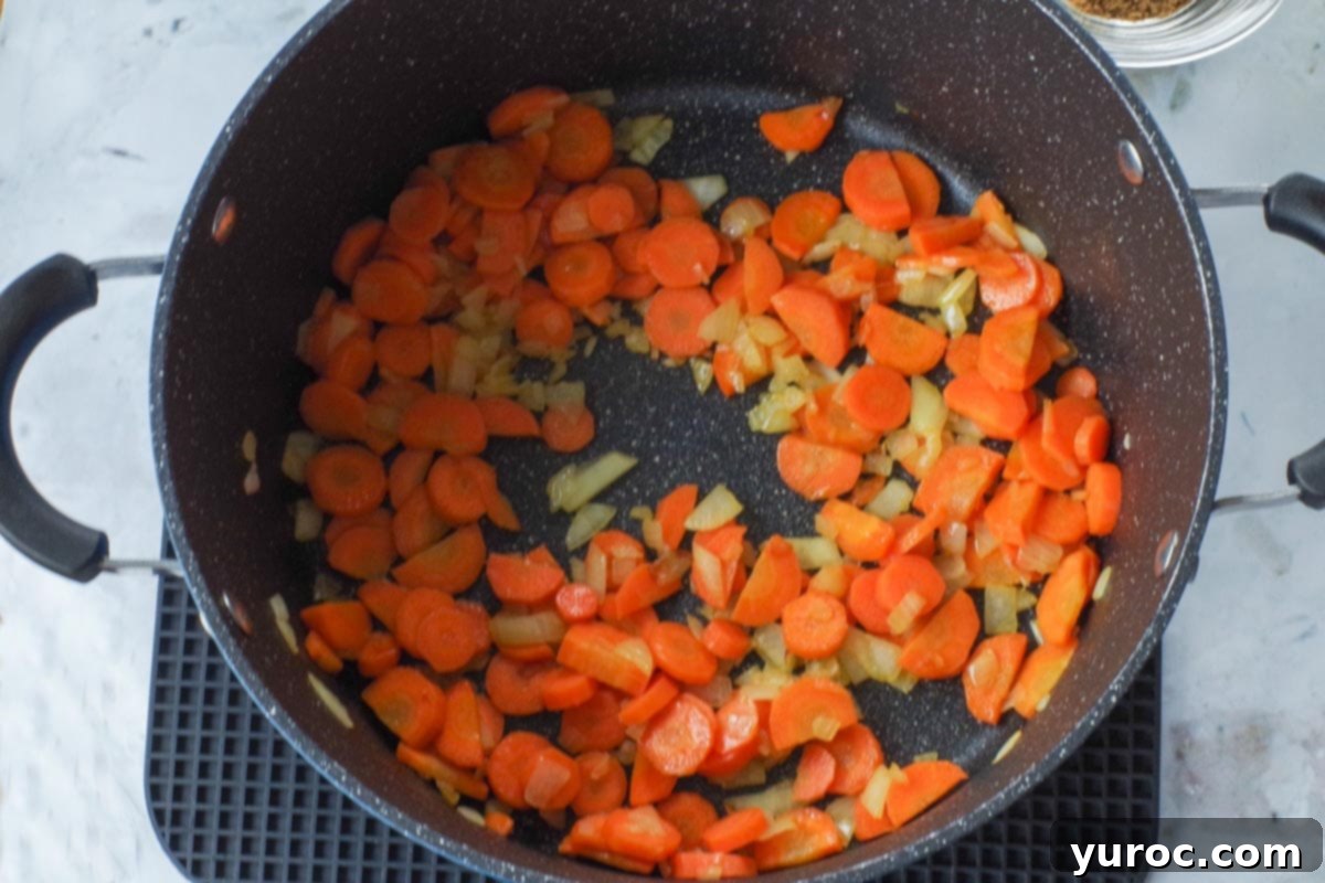 Carrots and onions sauteed in oil in a soup pot.