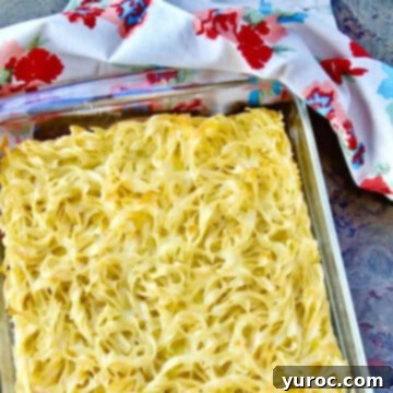 A comforting egg noodle casserole baked in a clear glass dish, with a soft paper towel in the background, highlighting its golden crust.