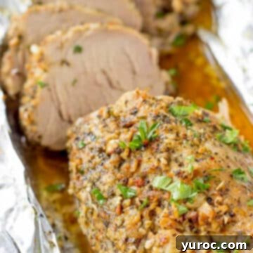 Slices of Ukrainian pork roast, known as Buzhenina, neatly arranged on a foil-covered pan, showcasing its tender texture and golden crust.