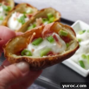 air fryer potato skin being held up over a tray of more air fryer potato skins